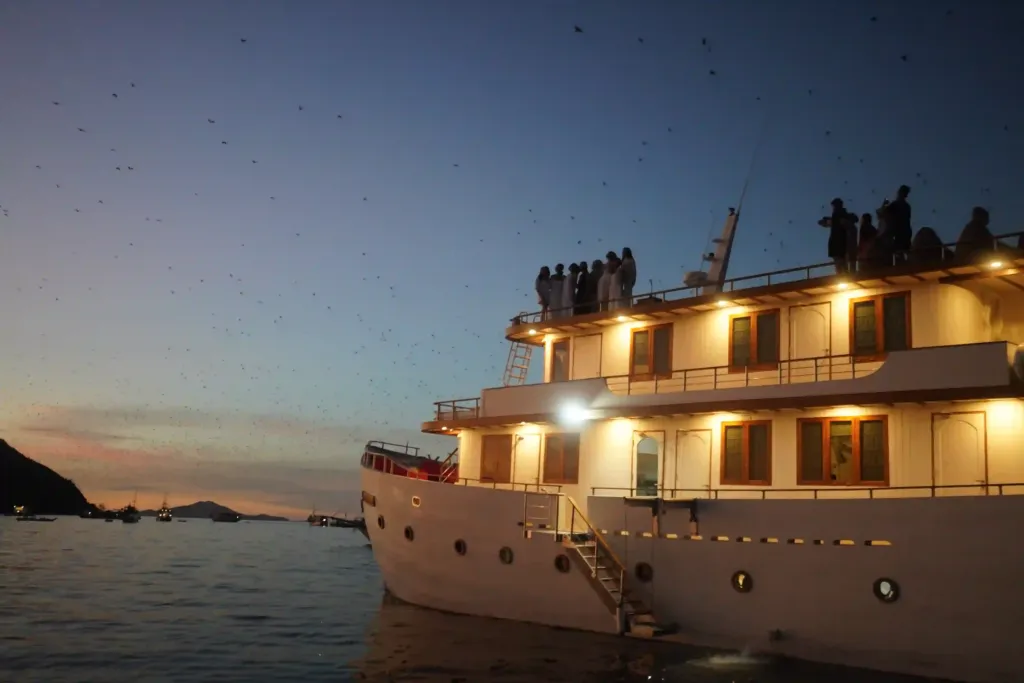 Guests on the top deck of a liveaboard at dusk near Kalong Island