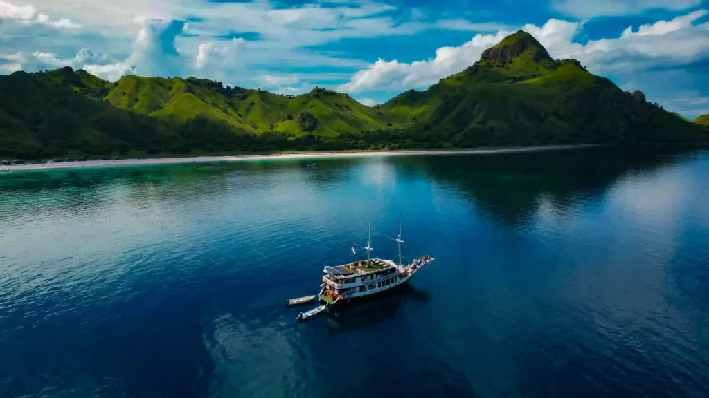 Bali to Komodo by sea: the phinisi Sukha Sail 1 at anchor in a green bay
