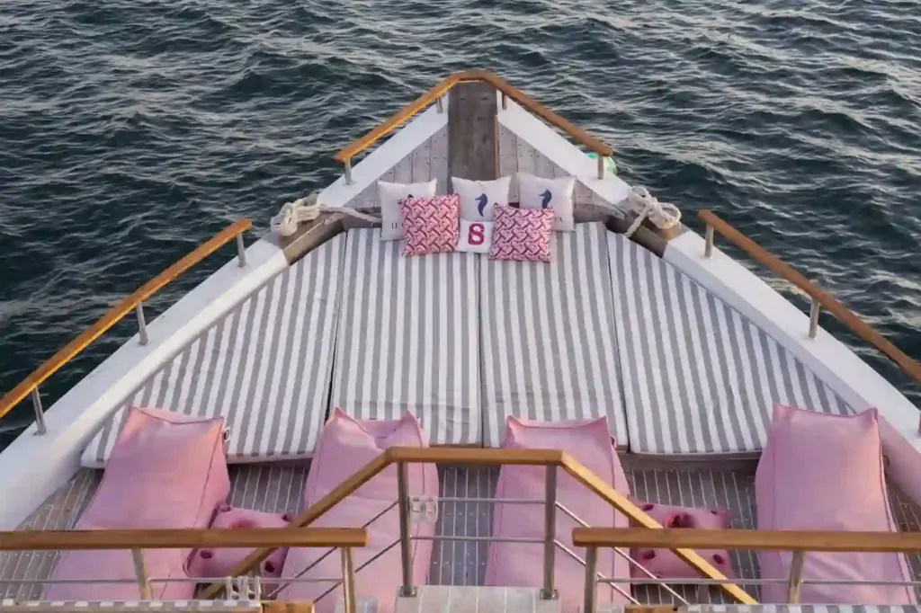 A cushioned lounge on the bow of a liveaboard with the sea beyond